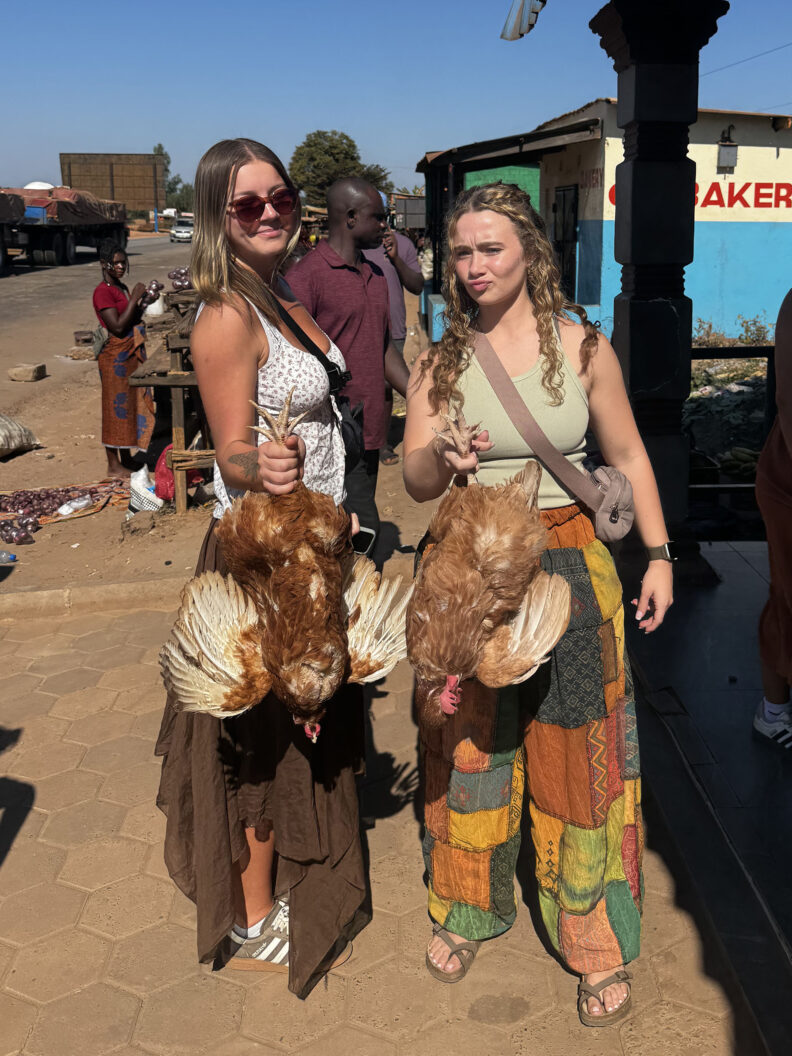 Fellow nursing students Ryley and Eva holding live chickens bought from the market in Baluba Village. Photo: Abigail Elliott.