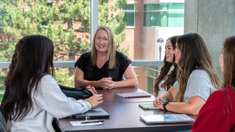 Dean Anne Mason, DNP, ARNP, PMHNP-BC, '02, '05, talking with a group of nursing students.