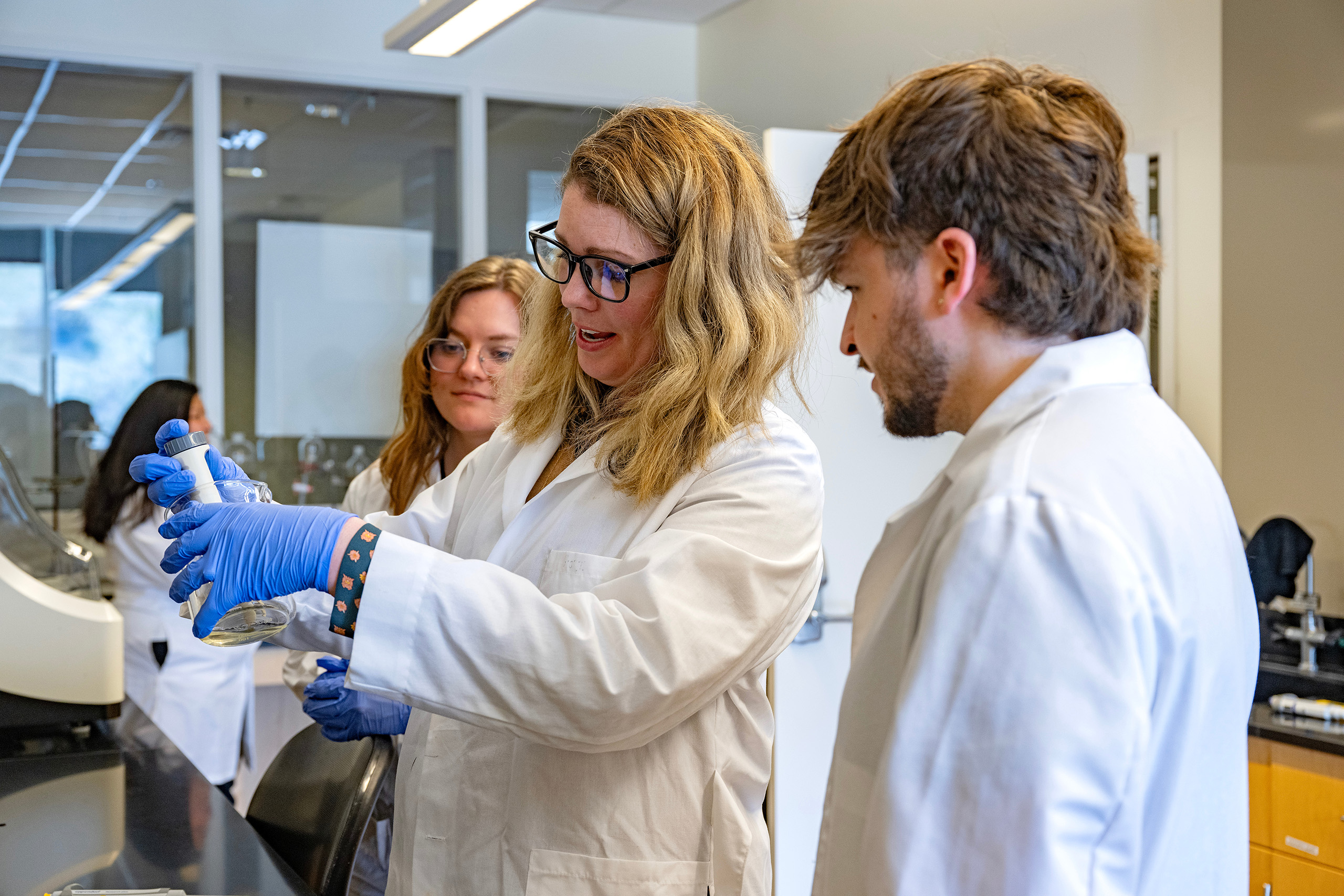 Kate Kraszewski with VCEA School of Design and Construction teaches students how to perform water sampling tests for a stormwater quality study being conducted on turfgrass.