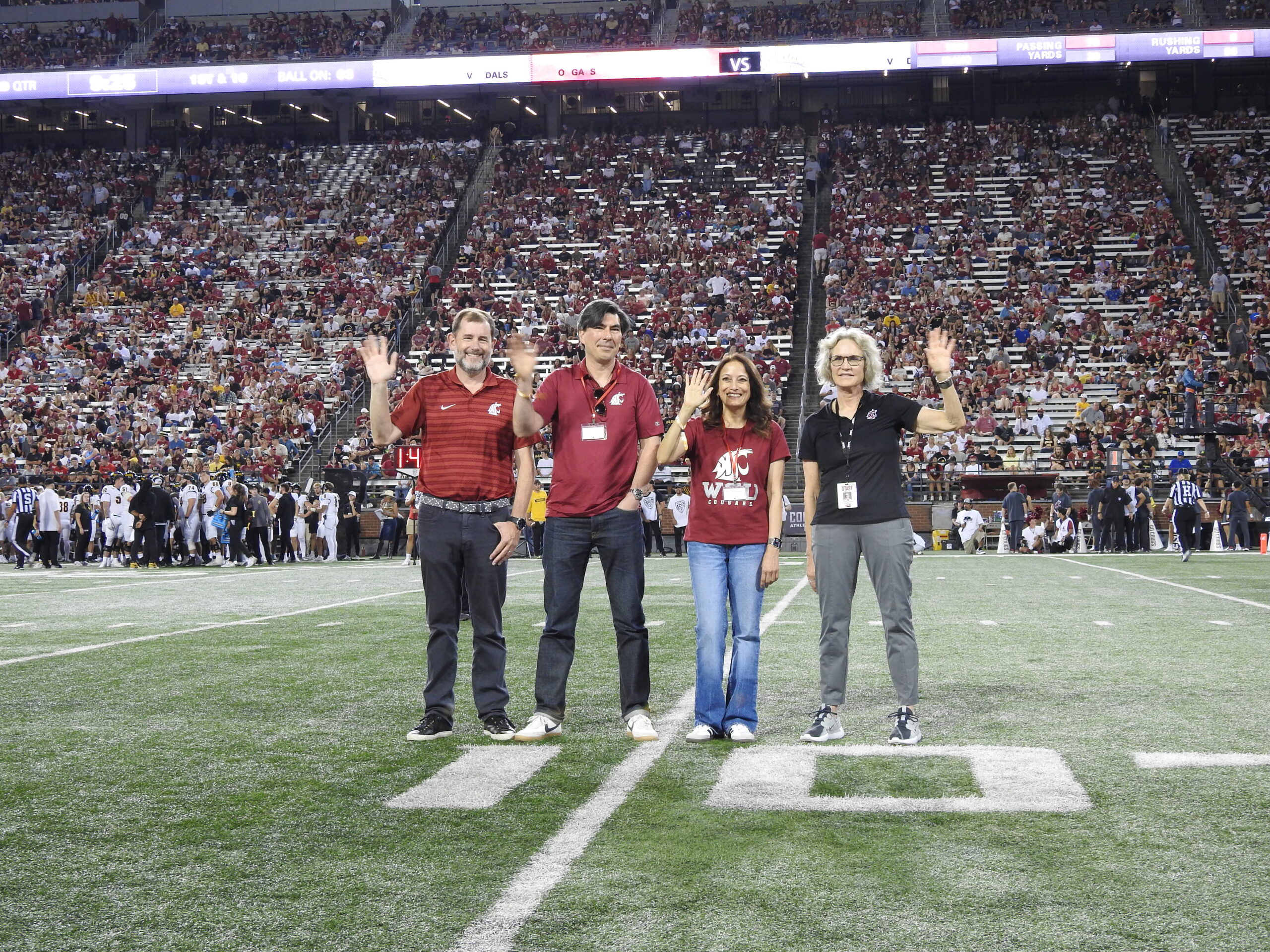 Provost Riley-Tillman, Porismita Borah, Ryan Driskell, and President Cantwell wave to the crowd at a Cougar football game on Gesa Field.