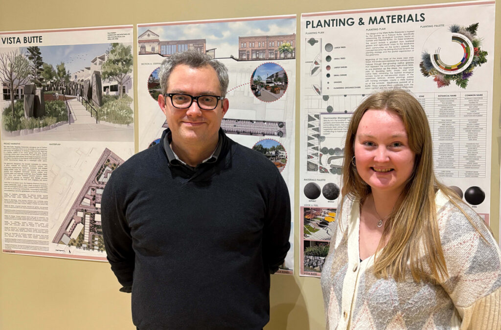Dan Cronan and Ella Roney stand before three posters detailing Roney's landscape designs. Poster titles “Vista Butte” and “Planting & Materials” are visible.
