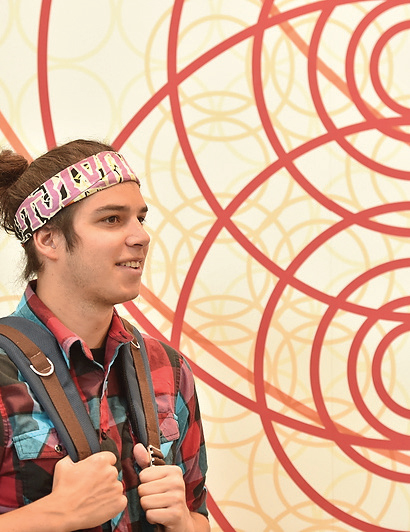 Student in colorful clothing stands in front of large wall graphic visually representing the Victory Bell.