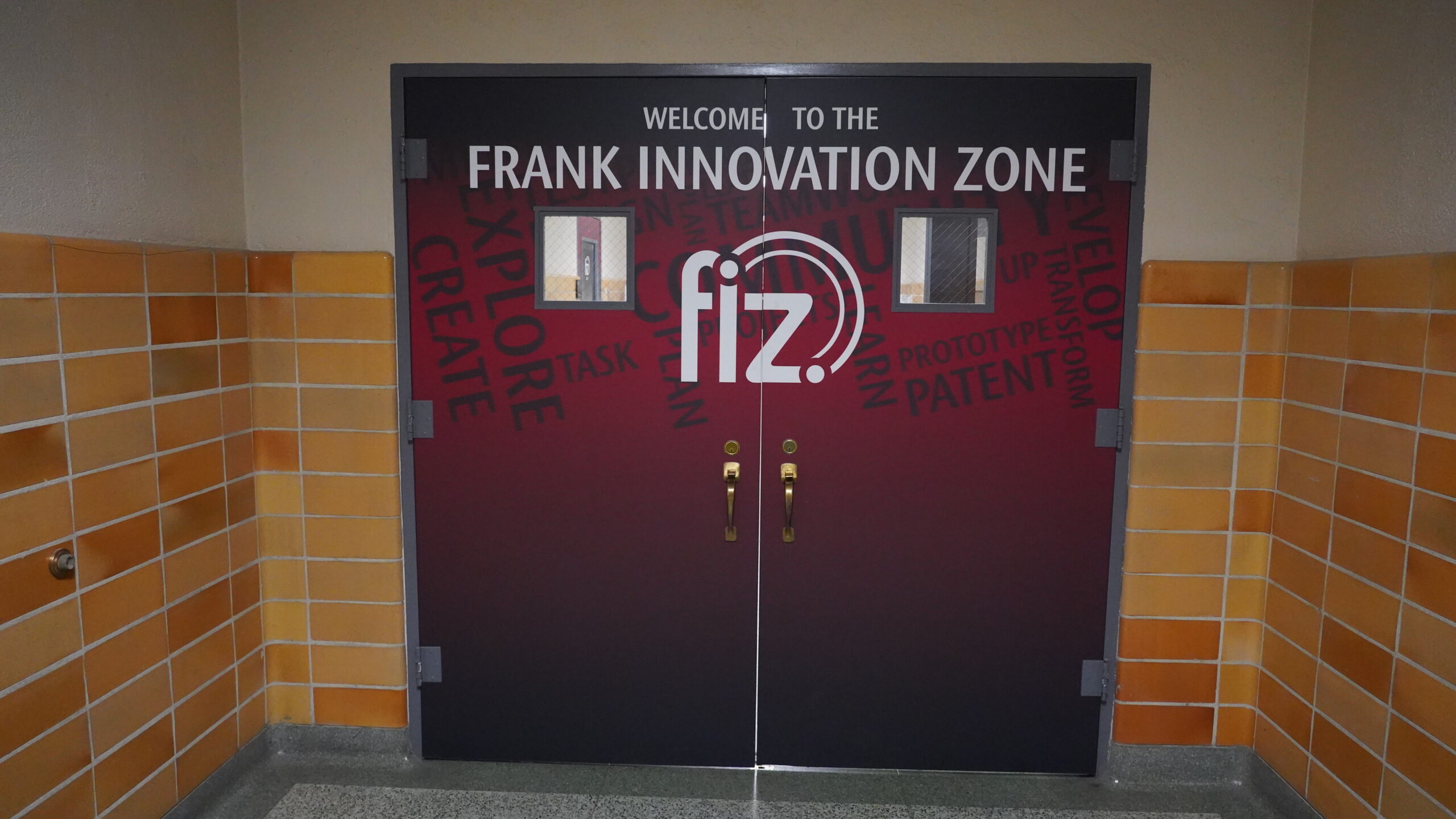 Hallway with double doors, handles and small windows. Doors are affixed with graphics indicating the entrance to the WSU Frank Innovation Zone.