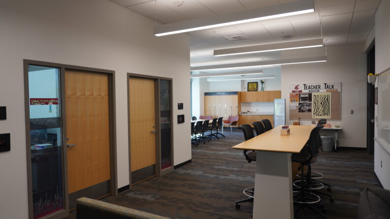 View of the Faculty Innovation Studio with two sets of tables and chairs, lockers in the back for storage.