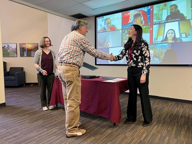 Richard Zack shakes hands with WSU Teaching Academy chair Kate Watts as his induction to the academy is formally recognized.