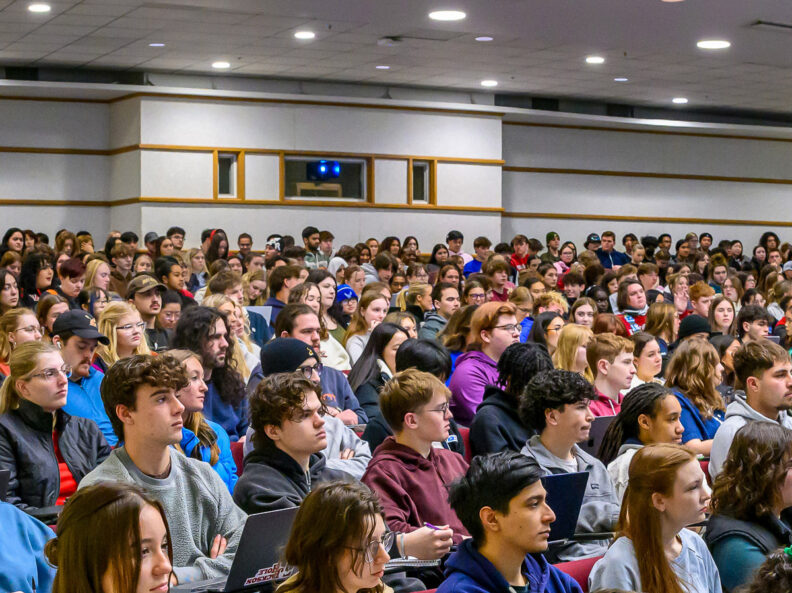 A large group of students listen to a lecture in an auditorium-style classroom on the WSU Pullman campus.