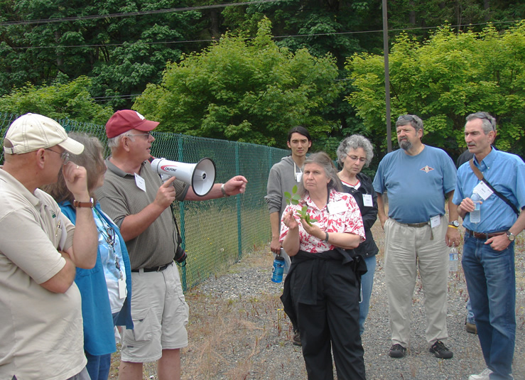 a man in a red hat with a megaphone speaking to a small group of people