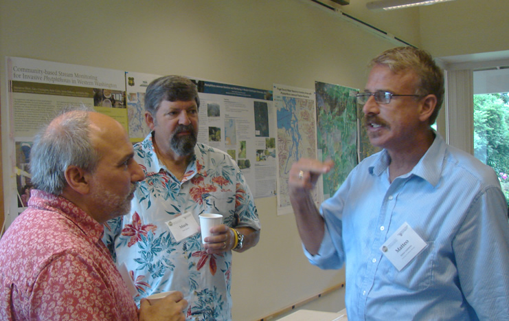 one man talking with a hand gesture, two men listening