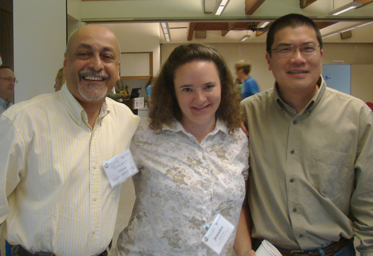 a smiling woman between two smiling men all posed for a picture