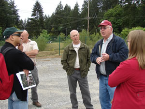 A man in a red cap is speaking to a small group of people