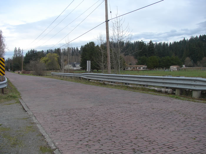 a cobblestone road with metal railings alongside it.