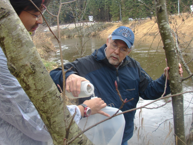 a man pouring a nalgene of water into a bag held by another man