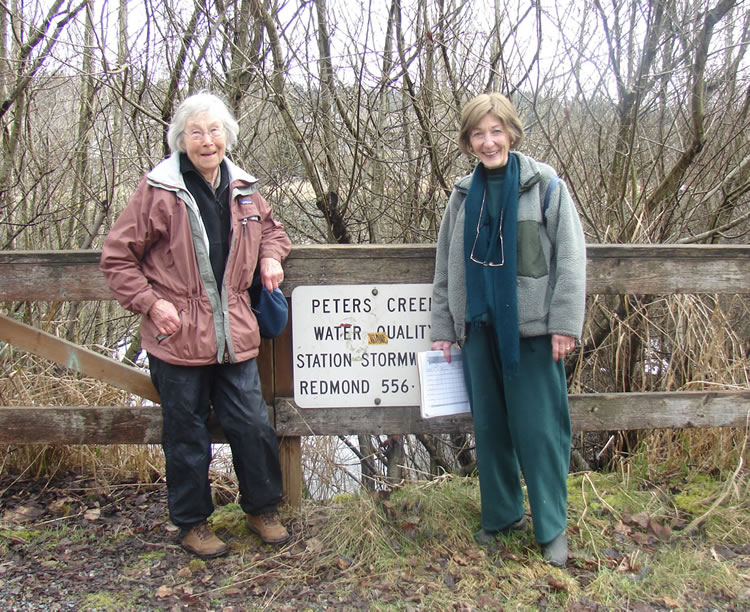 Smiling women standing by a sign for Peters Creek