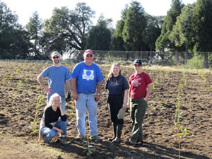 Four people standing and one kneeling in a field