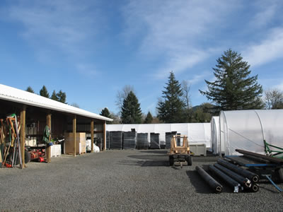 the yard between greenhouses and open-front storage sheds