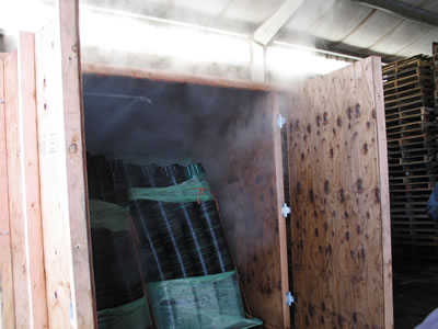 a steam room made of plywood filled with stacks of pots held together with plastic wrap