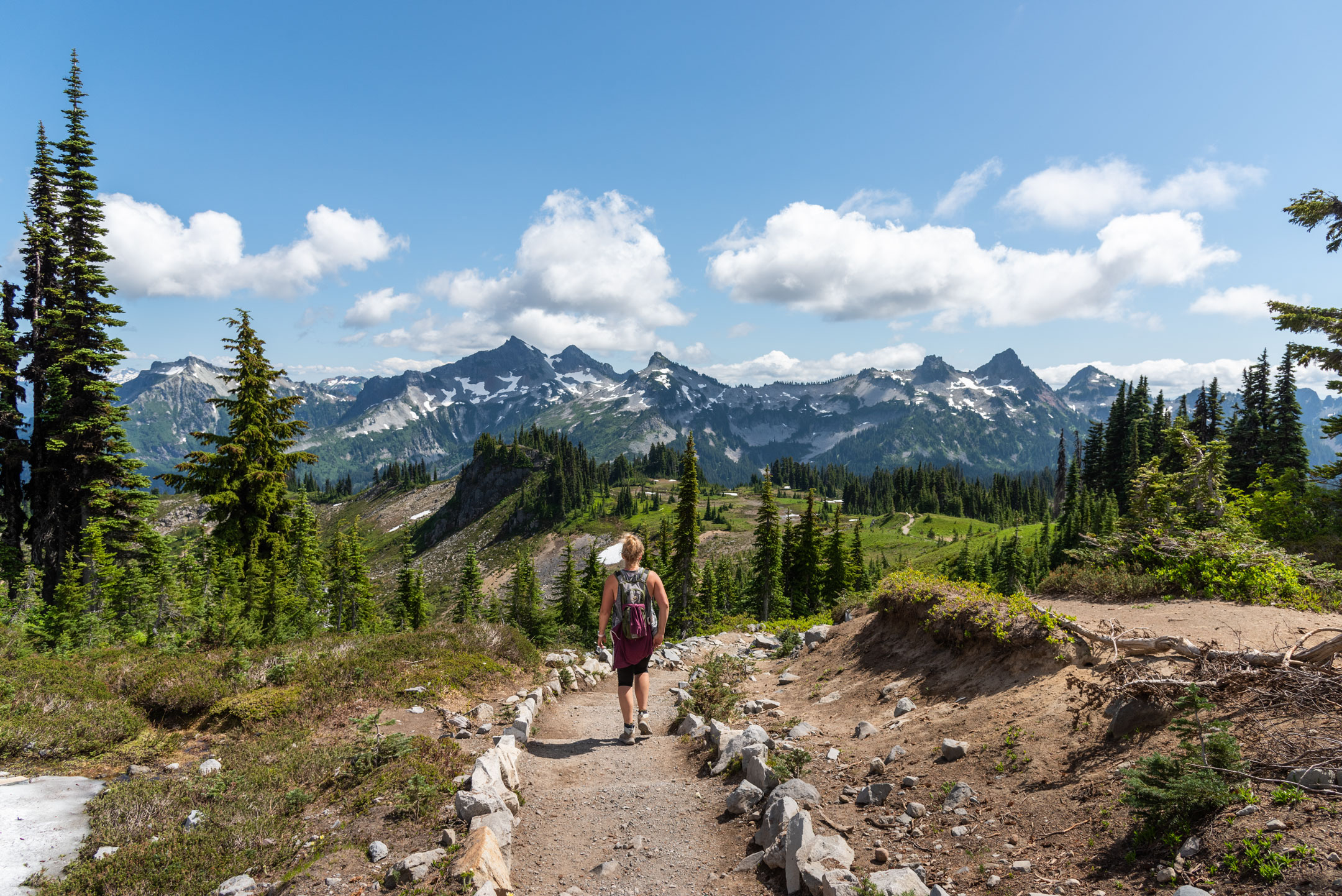 Woman hiking on trail through beautiful majestic mountains landscape in the stunning Mt. Rainier National Park, Pacific Northwest, Washington State.