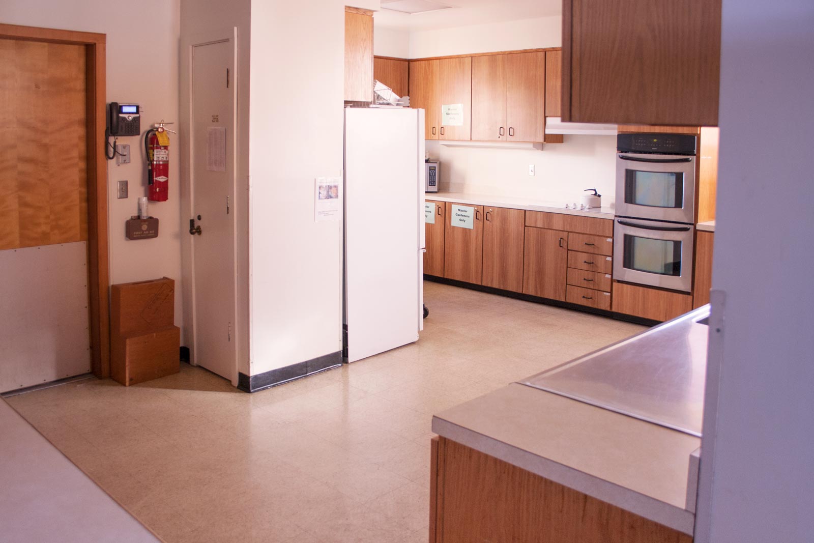 A large kitchen space. Double wall ovens and refrigerator in the background.