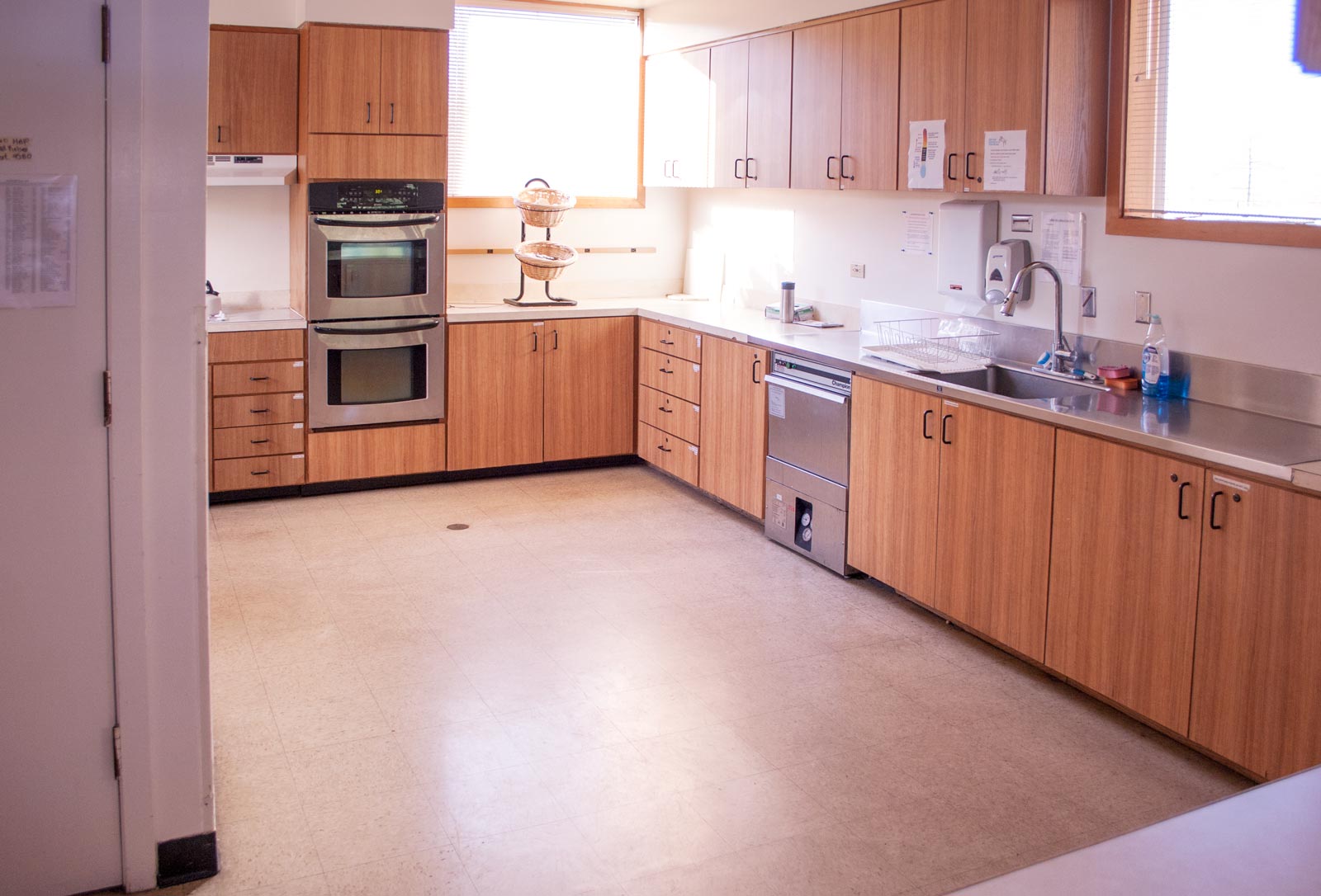 A large kitchen space with double wall ovens, dishwasher and sink.