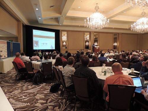 2013 Waste to Worth attendees watch a presentation from their tables.