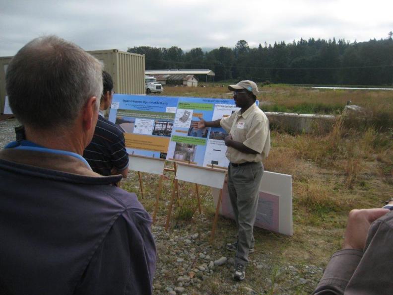 Man speaks next to posters during an educational site visit.