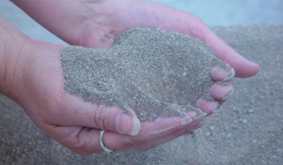 Larger image of hands holding processed struvite.