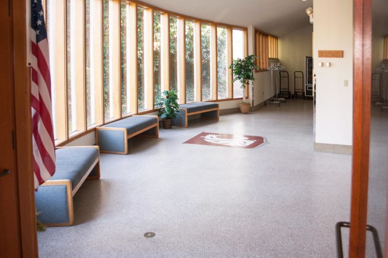Building lobby with three benches and panoramic window onto garden area.