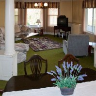Living room with seating around a television, and formal dining room.