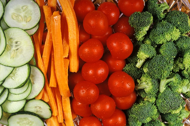 Cut vegetables including sliced cucumbers, carrots, cherry tomatoes, and broccoli.
