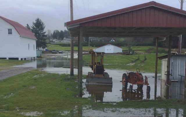 Tractors parked under a flooded farm shelter