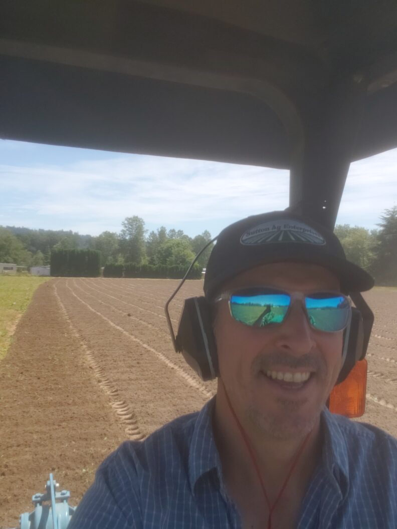 Person on a tractor with tilled field in the packground