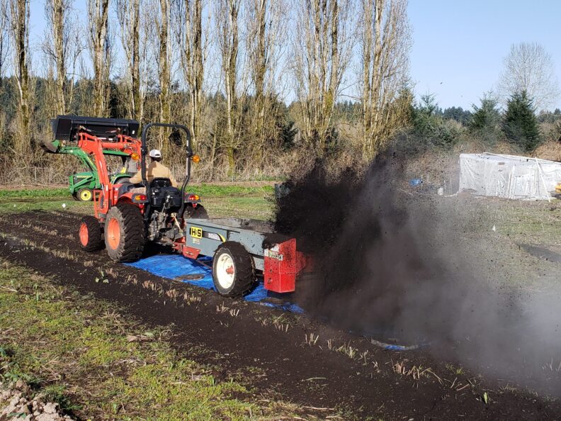 Compost spreader calibration over a tarp laid in a field.