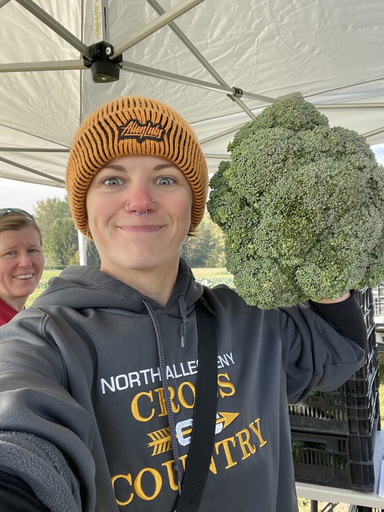 Researcher holding a broccoli plant near their head