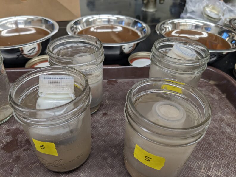 seaweed amended soil was separated into particulate organic matter and mineral-associated organic matter to quantify soil carbon changes in these fractions. photo shows jars of soil and dispersant solution used in high throughput method of physical fraction