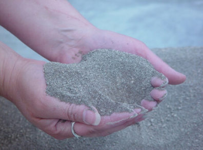 Hands holding a small pile of struvite.