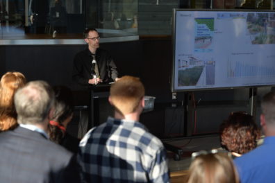 A photo of a faculty member giving a presentation and the audience watching