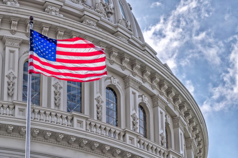 The US flag flying in front of the US Capitol Building in Washington, DC.