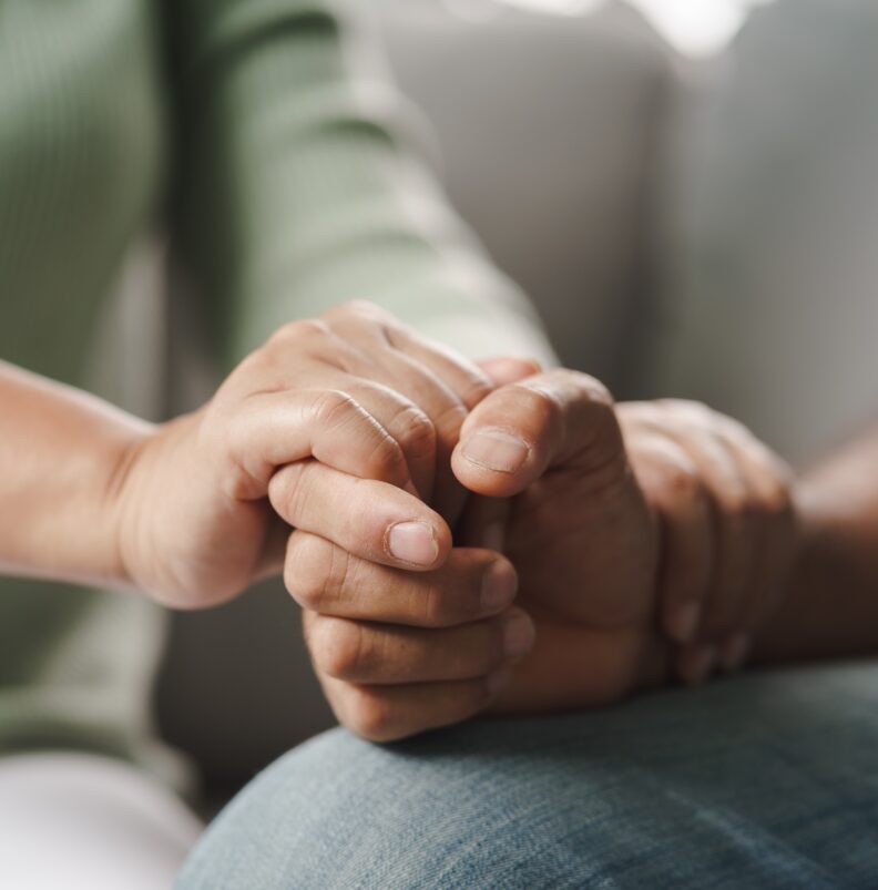 A woman holds someone's hand during counseling.