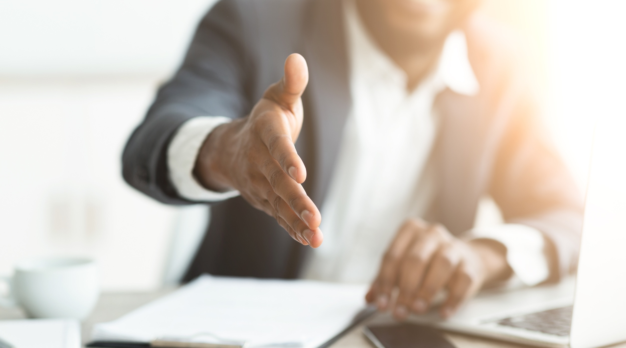 Man offering a handshake across a table.