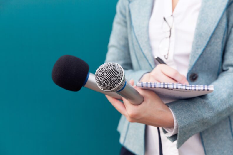 Person with microphones and a notebook for interviews.