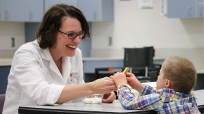 Carolyn Ross at a table interacting with a child.