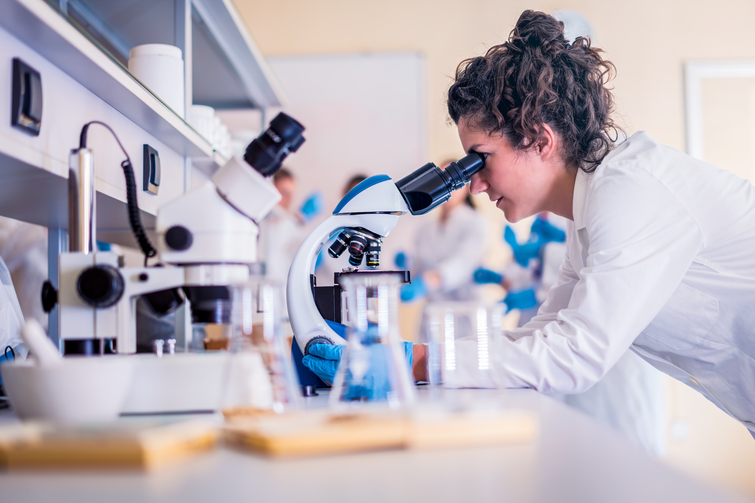Young female scientist looking through a microscope in a laboratory doing research.