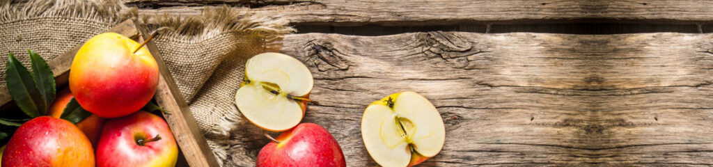 Full and half apples on wooden surface.