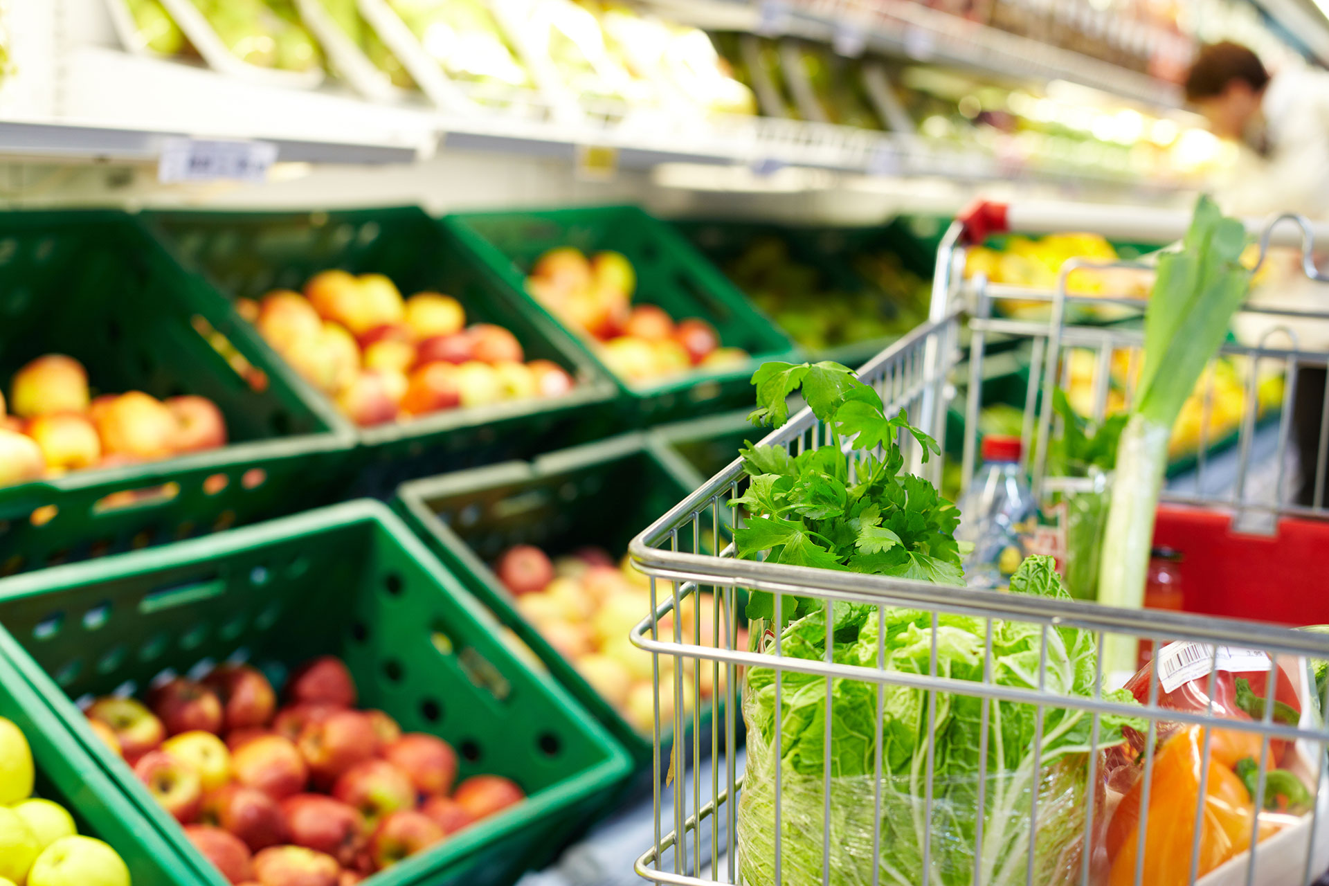 A shopping cart full of veggies in the produce section of the store.