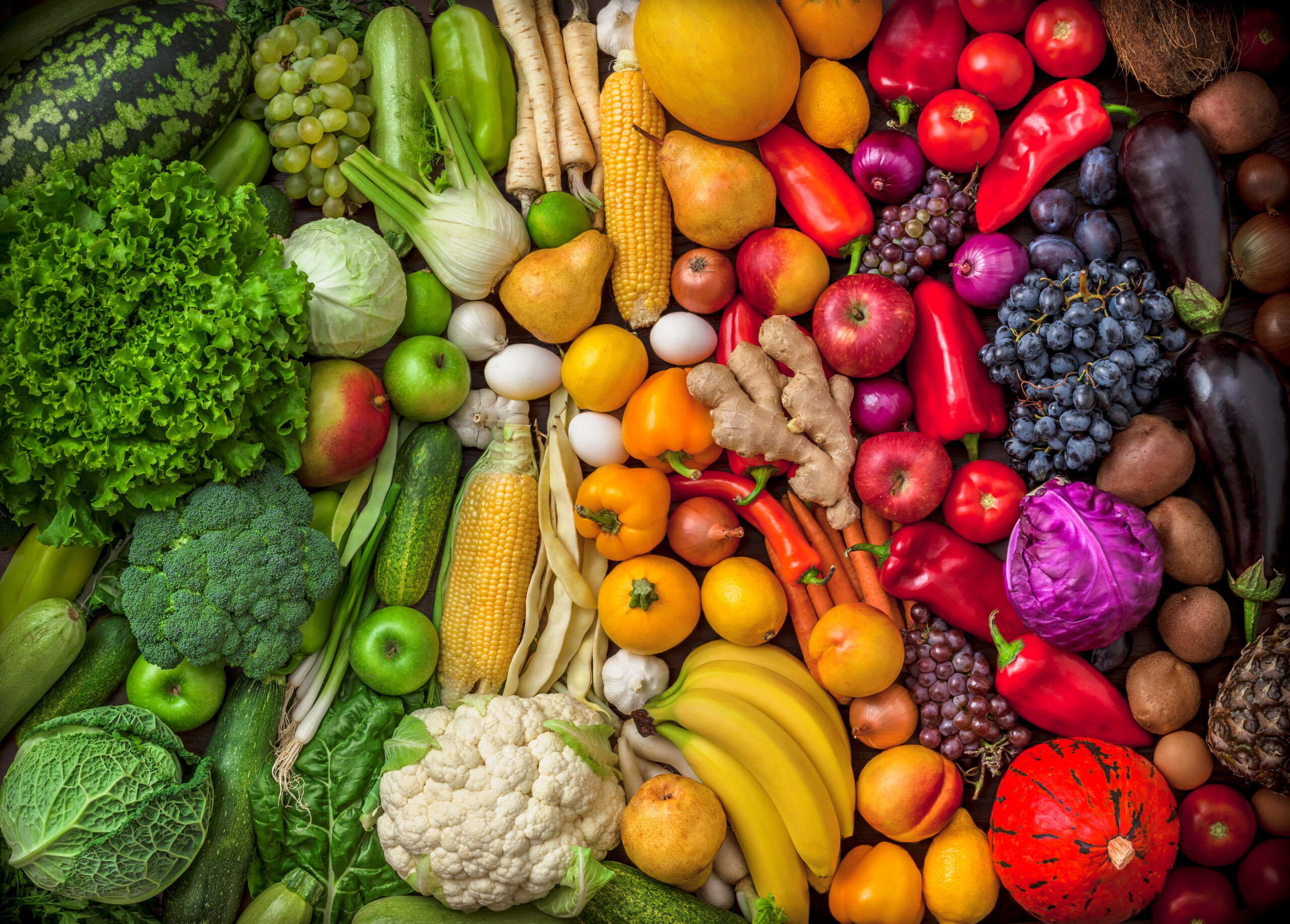 Fruits and vegetables background large overhead colorful mix green to red in studio. Green, white, orange, red.
