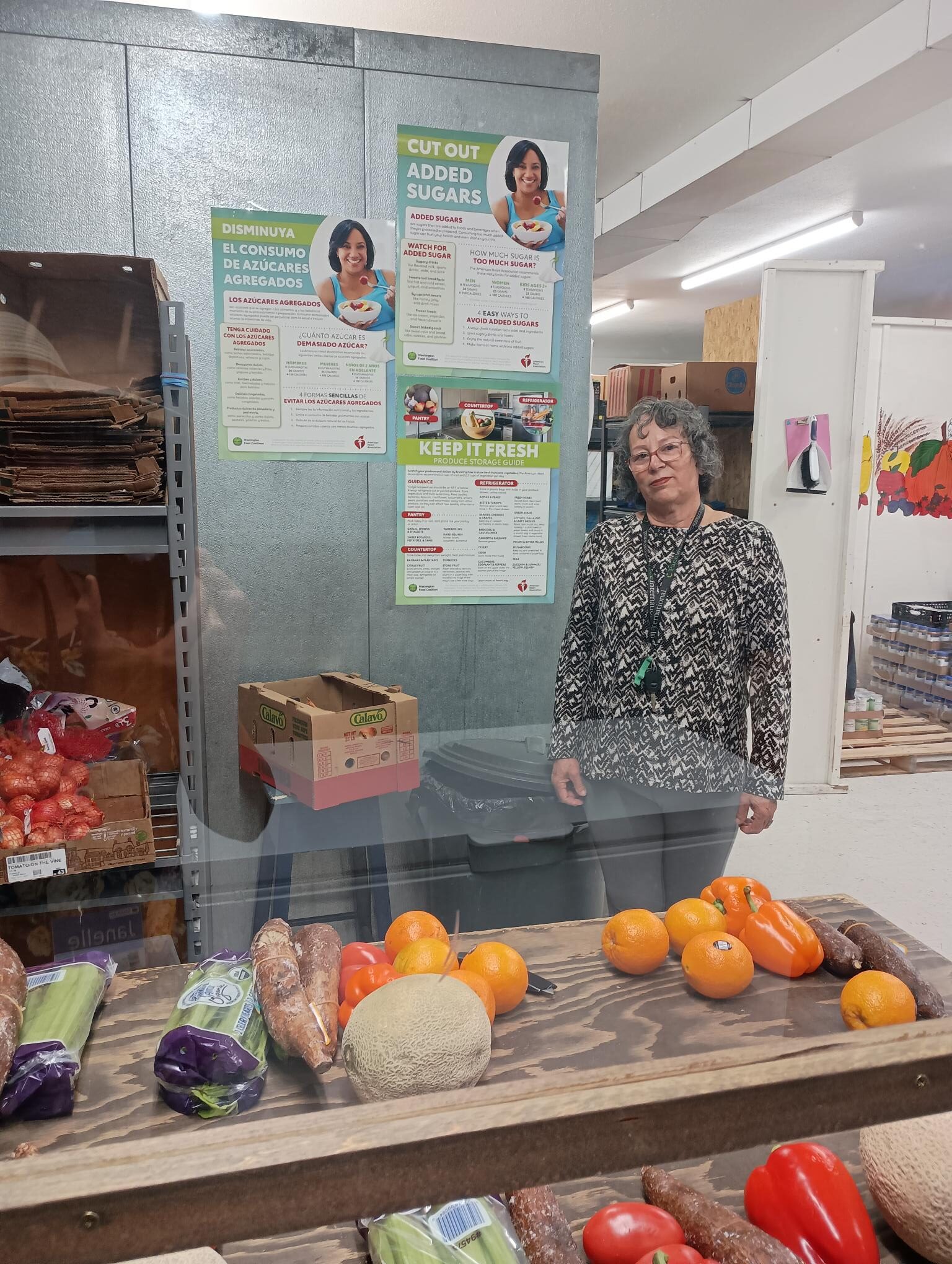 Food bank with posters, staff member, and fresh produce on shelf