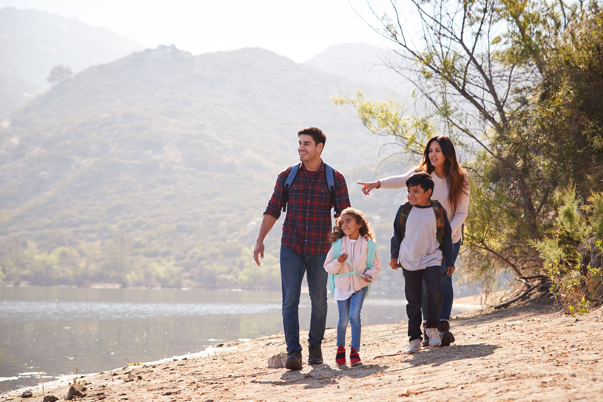 A mother, father, and two children walking around a lake.