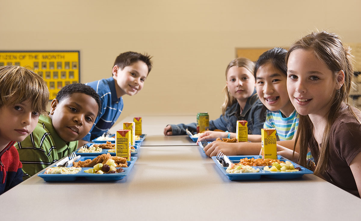 Children sitting around a lunch table with their lunch trays.