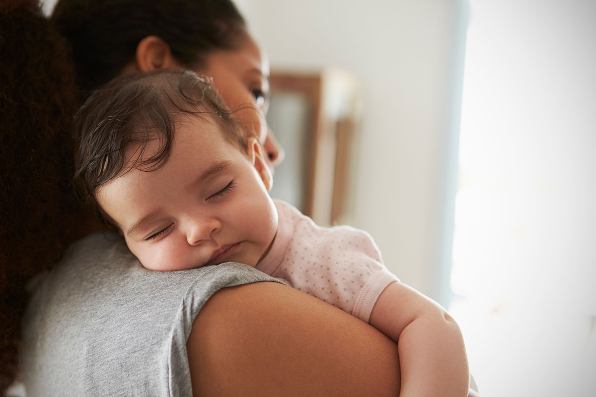 Mother holding a baby against her shoulder.