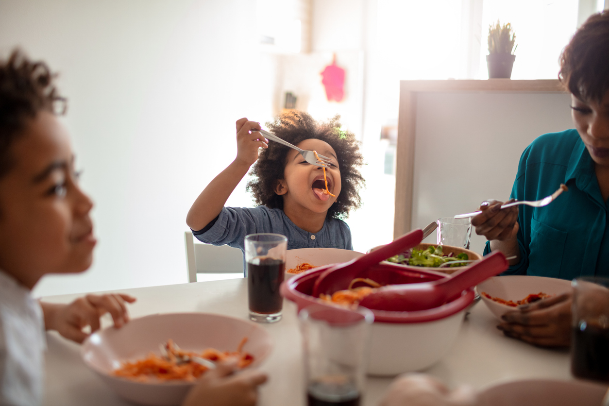 Mother and two children having lunch at the table at home.